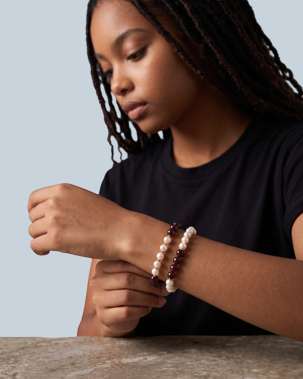 Pearlystones beaded bracelet featuring alternating white pearls and deep red garnet gemstones on a model's wrist.
