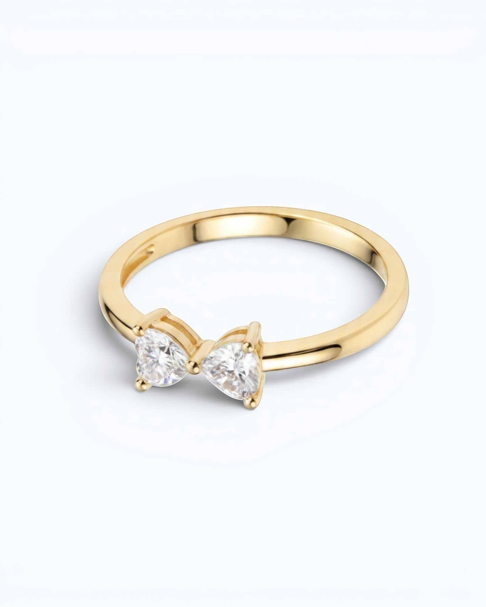 Pearlystones gold ring with a delicate bow design adorned with two heart-shaped gemstones.