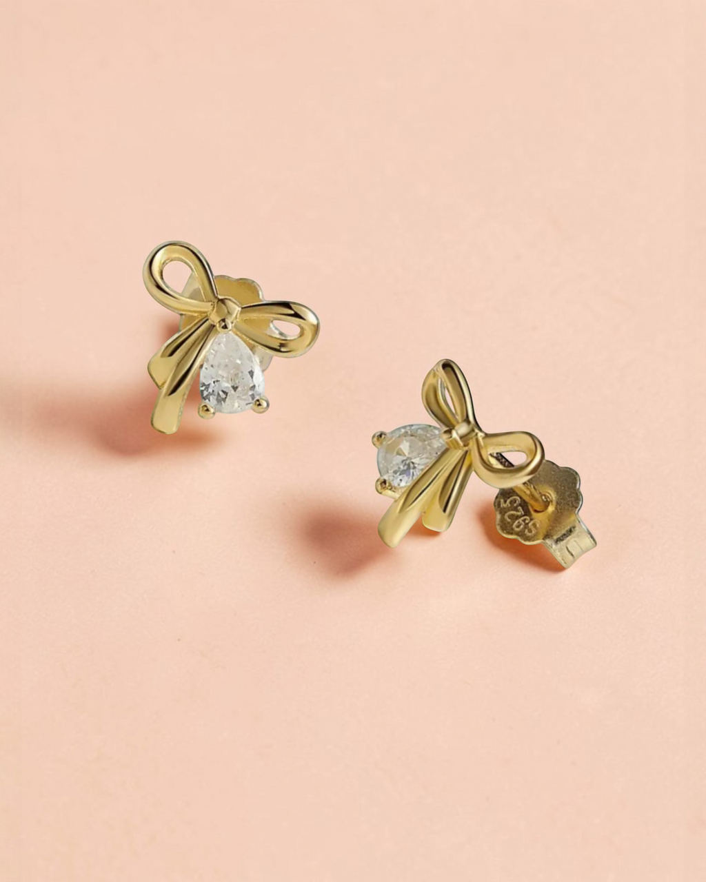 Pearlystones gold plated bowknot stud earrings with pear-shaped zirconia.