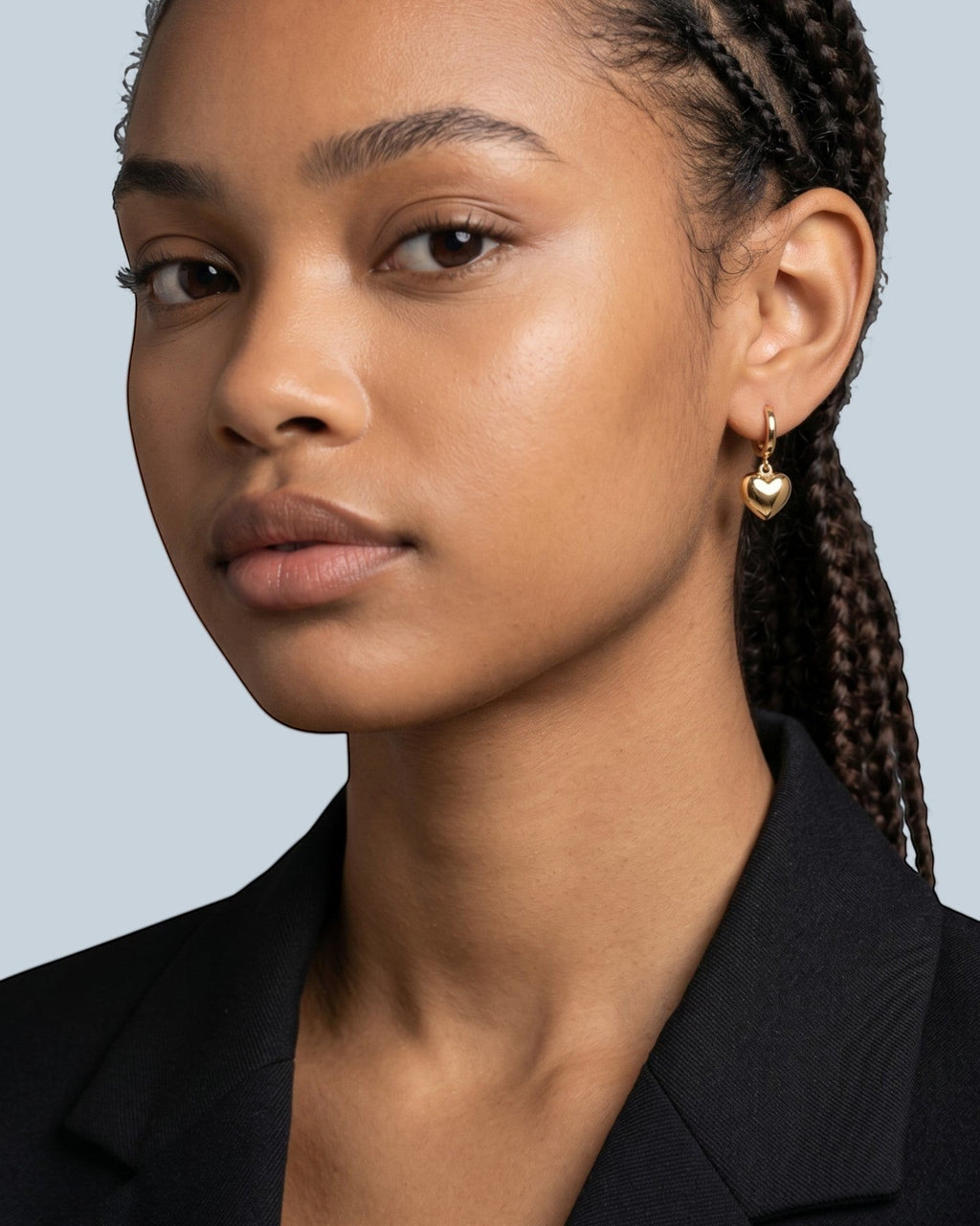 Pearlystones gold heart charm hoop earring on a model's ear.