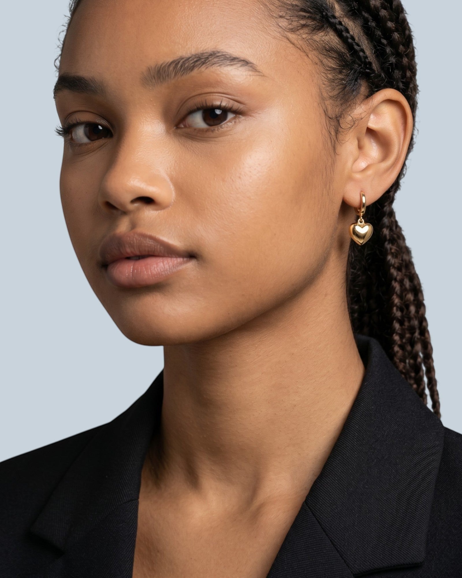 Pearlystones gold heart charm hoop earring on a model's ear.