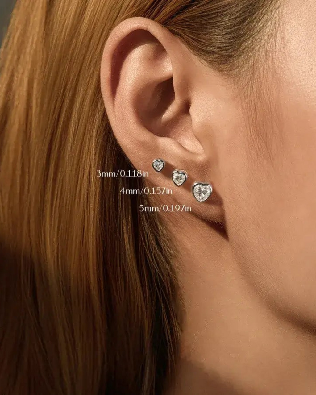 Pearlystones 5mm heart-shaped moissanite stud earring in rhodium-plated sterling silver worn on an earlobe