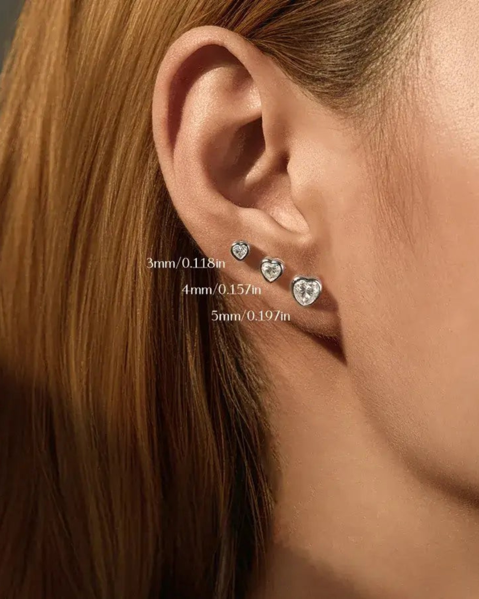 Pearlystones 5mm heart-shaped moissanite stud earring in rhodium-plated sterling silver worn on an earlobe