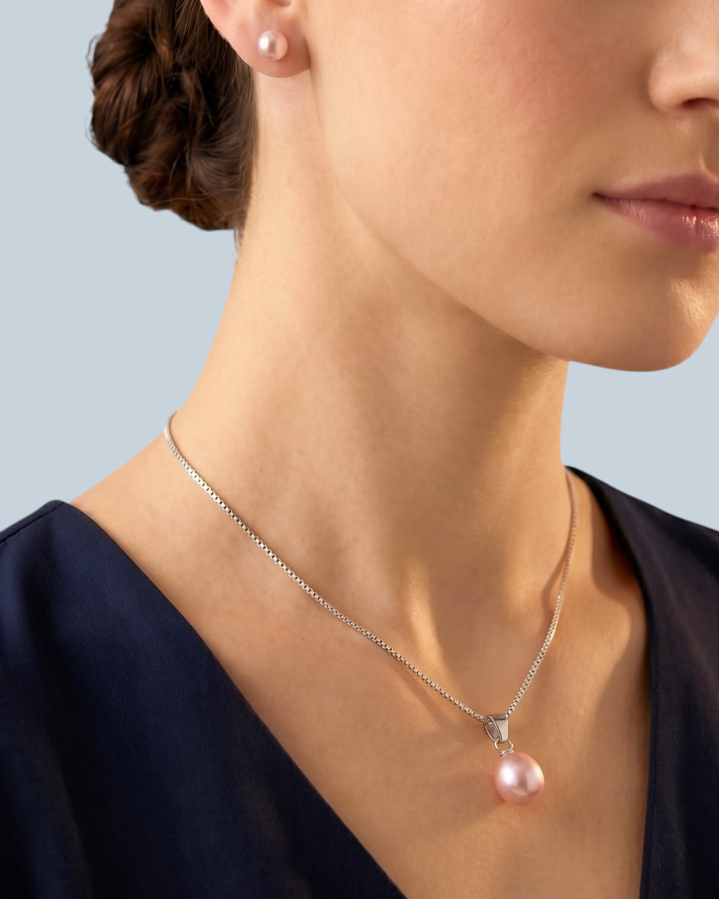 Pearlystones pink teardrop pearl pendant necklace on a rhodium plated silver chain worn by a woman