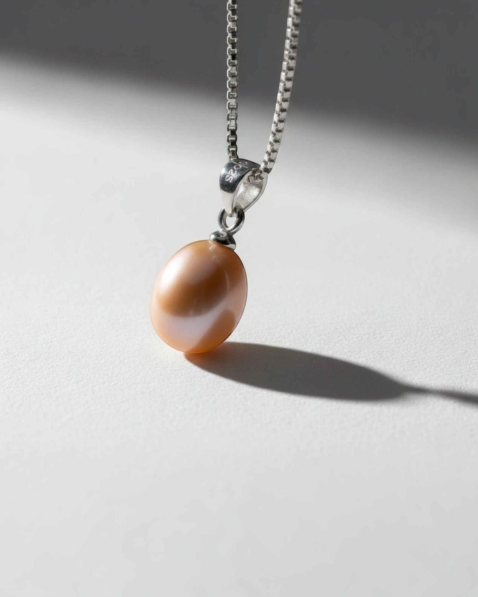 Pearlystones pink teardrop pearl pendant on a delicate rhodium plated silver box chain against a neutral background.