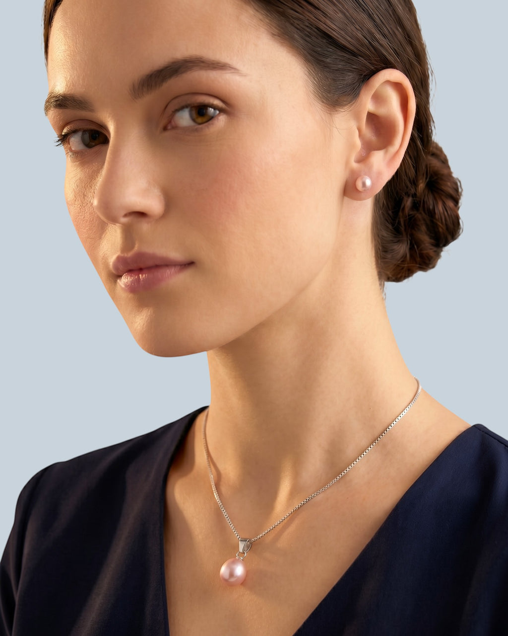 Pearlystones pink teardrop pearl pendant necklace on a rhodium plated silver chain worn by a woman