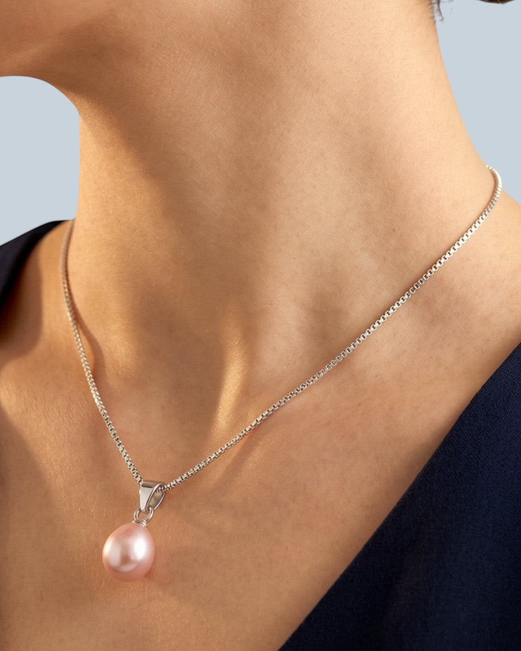 Pearlystones purple teardrop pearl pendant on a delicate rhodium plated silver chain worn by a woman