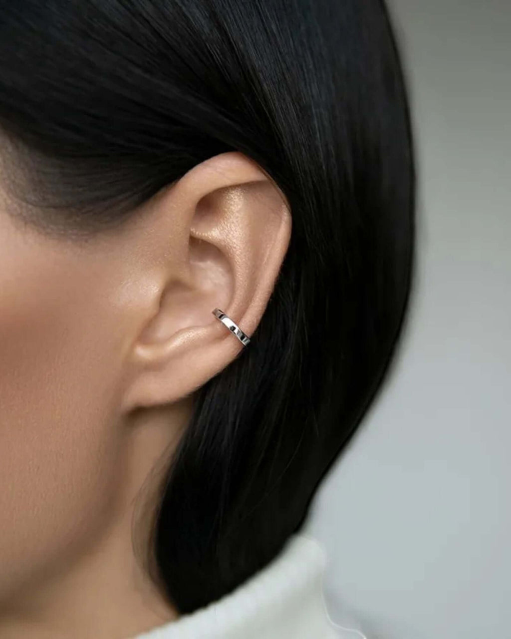 Silver ear cuff on a model’s ear showcasing non-piercing design and sleek styling.