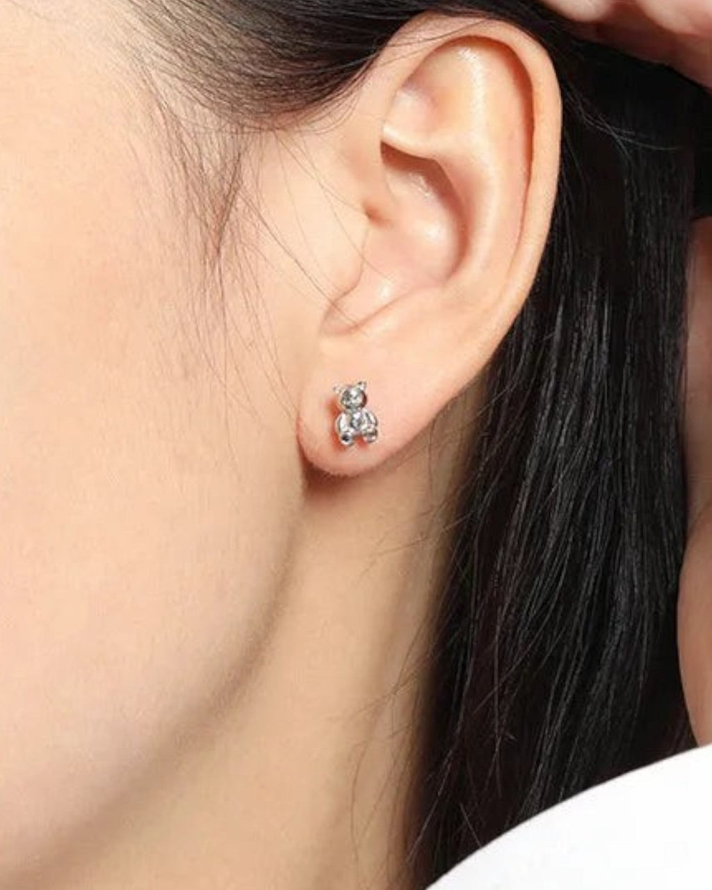 Pearlystones 3D teddy bear stud earrings in polished sterling silver worn on a woman's earlobe