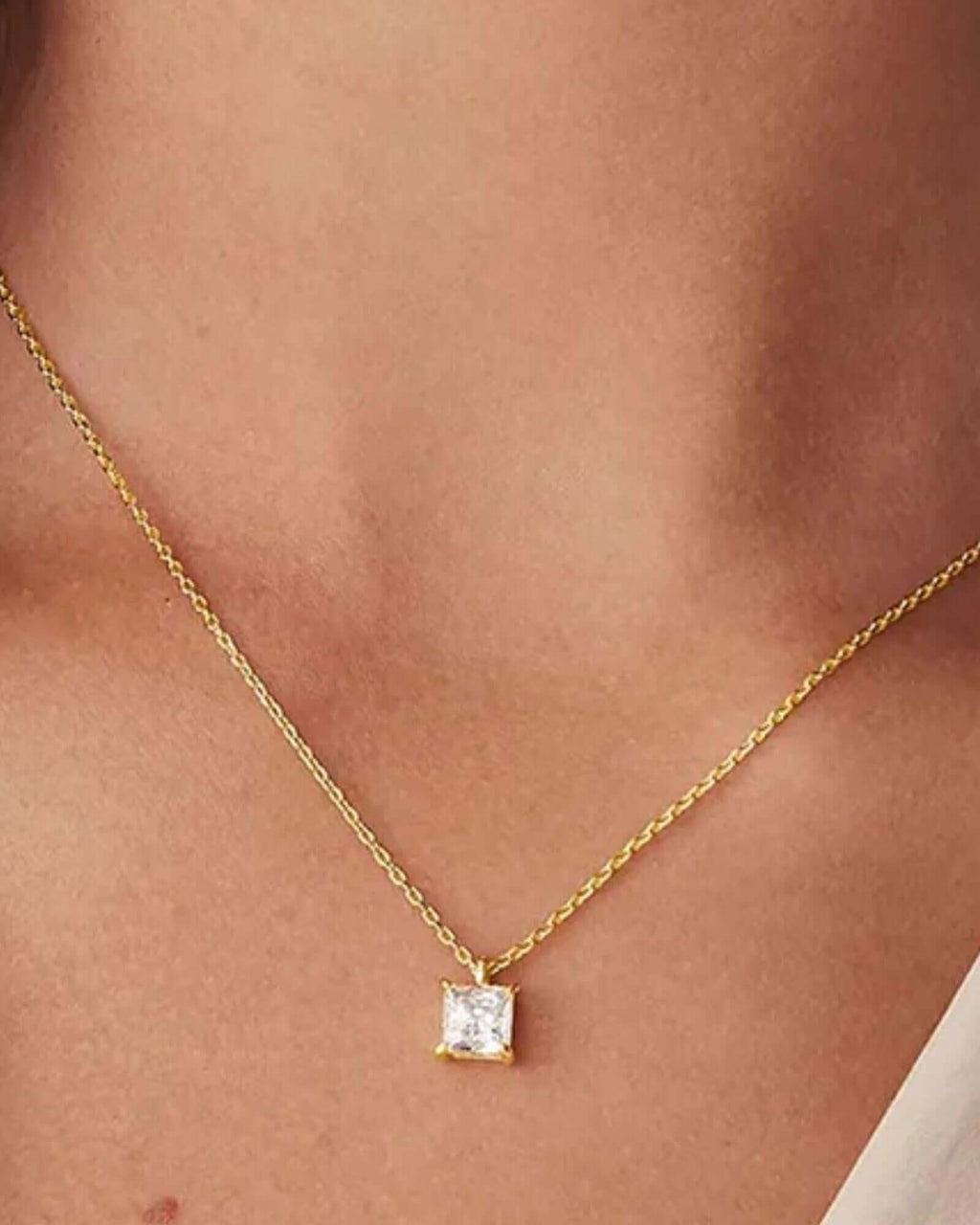 Pearlystones square zircon pendant necklace on a delicate gold chain worn around a person's neck