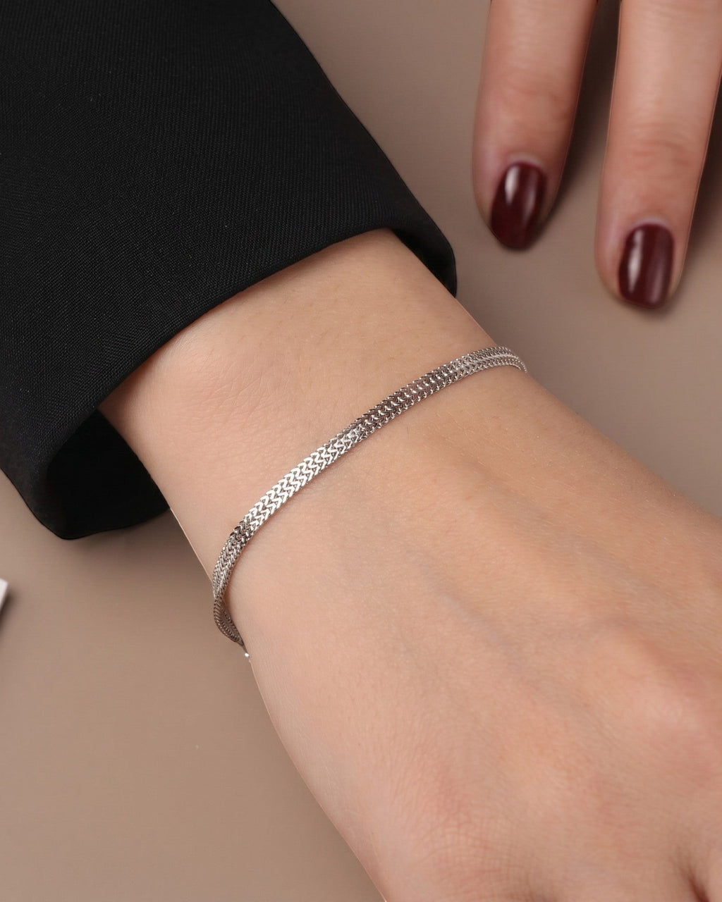 Pearlystones sterling silver double mesh chain bracelet worn on a wrist with a black blazer sleeve.
