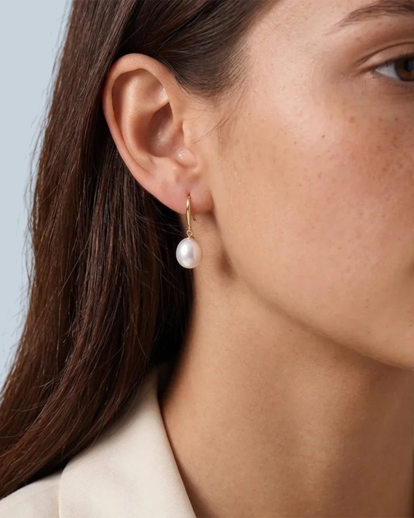 Pearlystones classic white pearl drop earrings in gold-plated sterling silver, worn by a model.