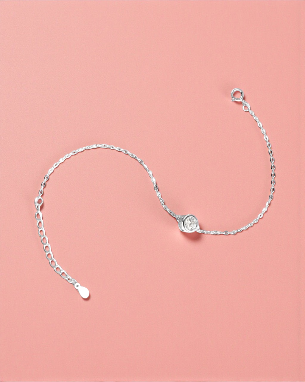 Silver bracelet with a clear gemstone on a pink background