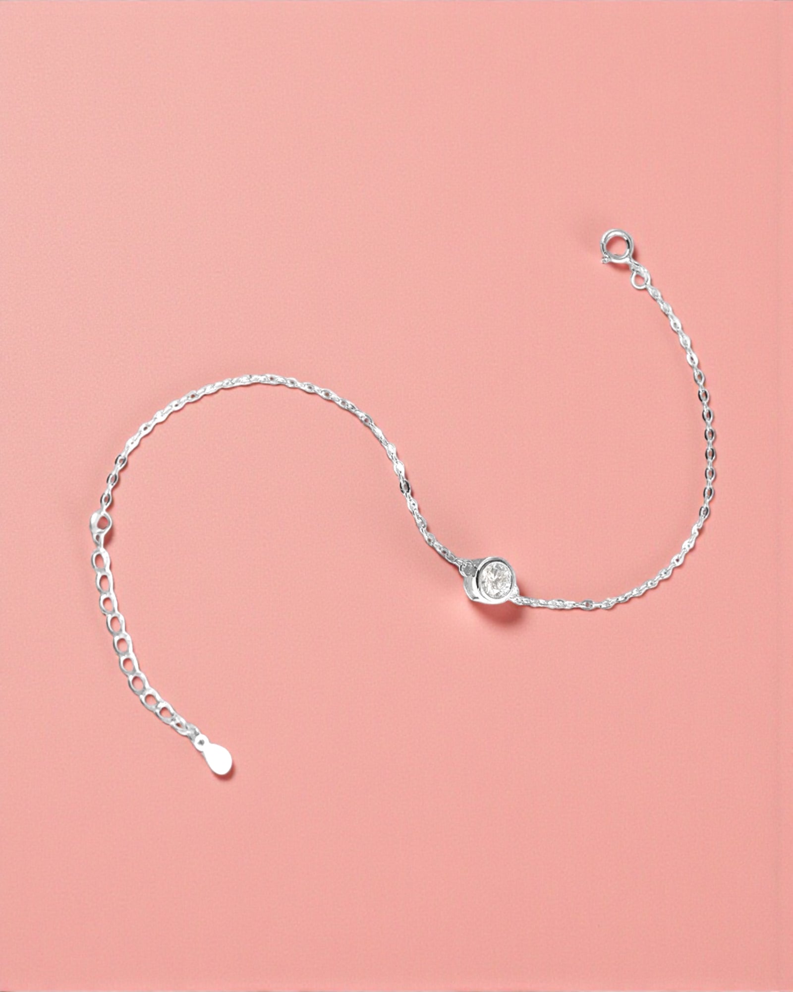 Silver bracelet with a clear gemstone on a pink background