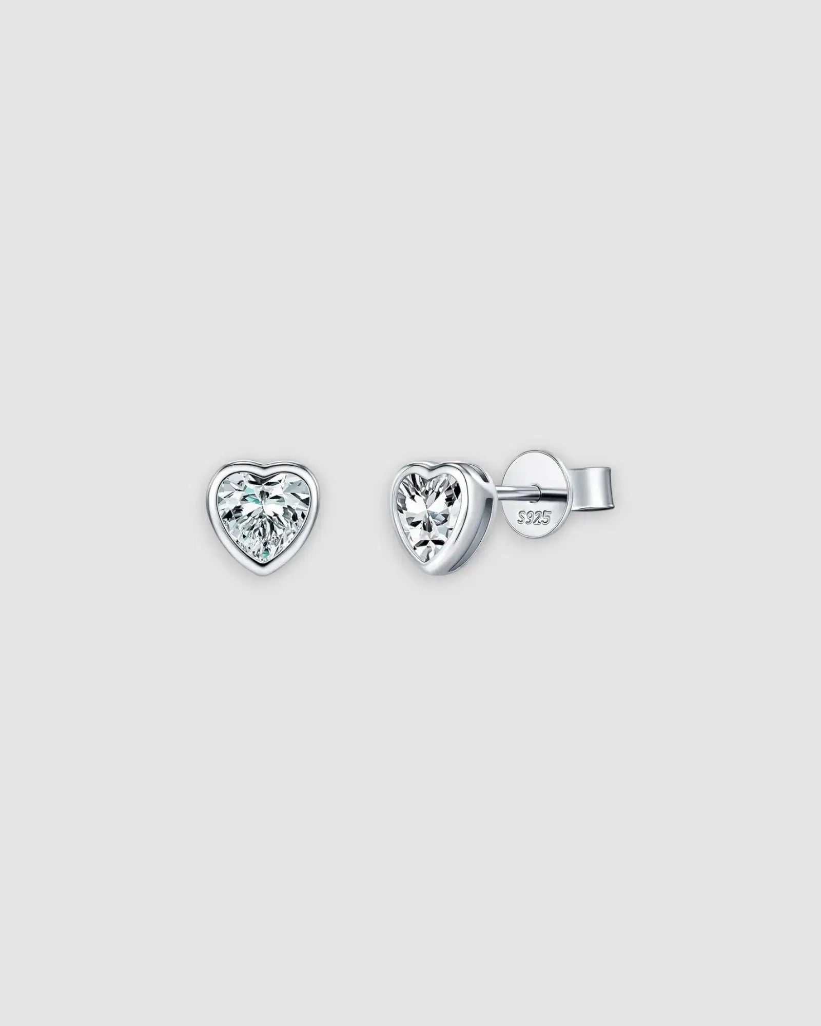 Heart-shaped diamond stud earrings on a light gray background