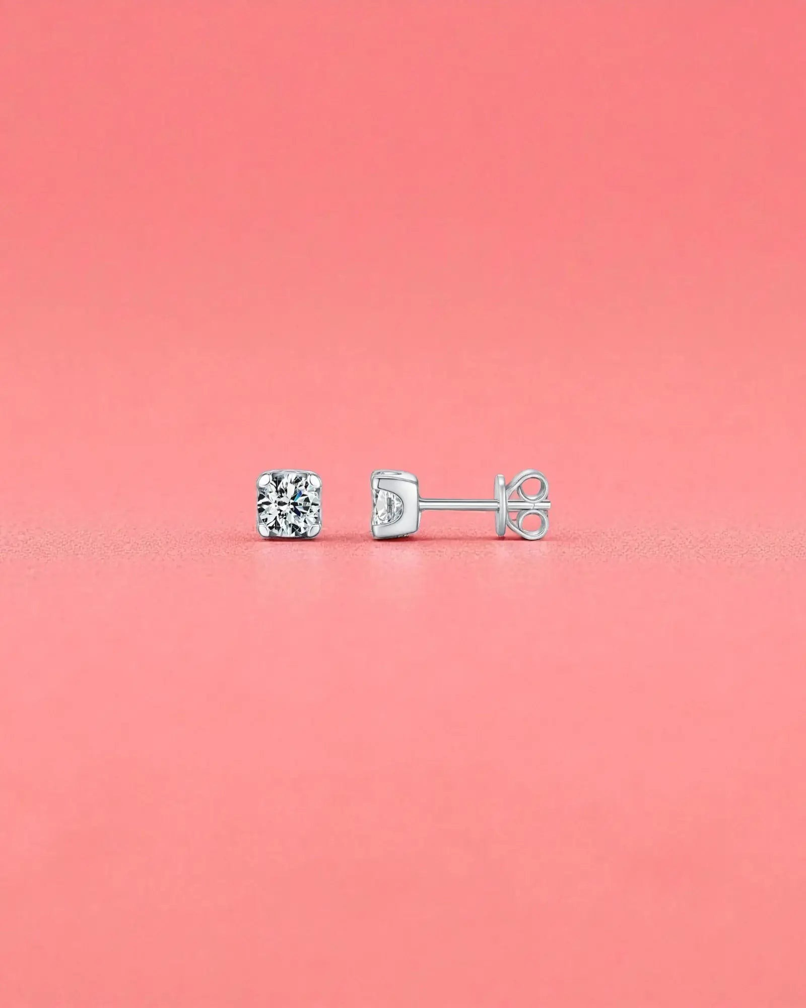 5mm Round brilliant cut moissanite studs with sterling silver and rhodium finish on a pink background.