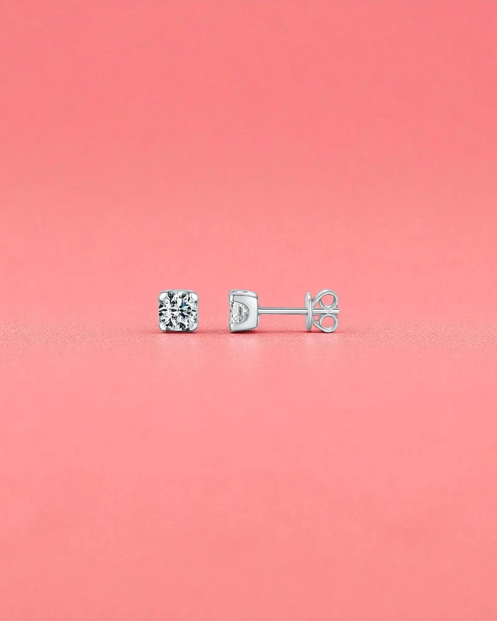 5mm Round brilliant cut moissanite studs with sterling silver and rhodium finish on a pink background.