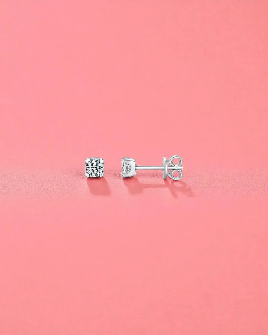 4mm Round brilliant cut moissanite studs displayed on a pink background, showcasing their brilliant sparkle and sterling silver setting.