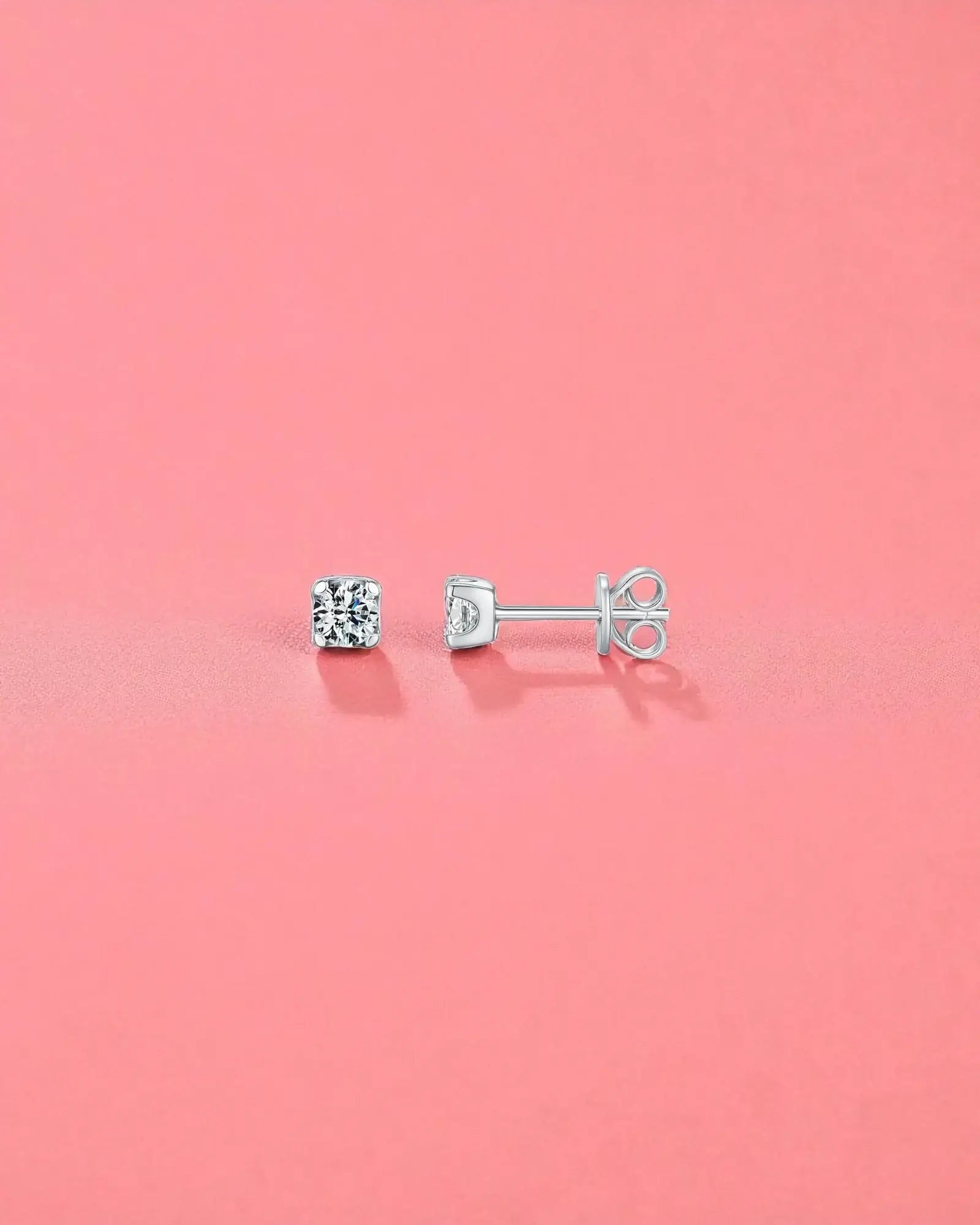 4mm Round brilliant cut moissanite studs displayed on a pink background, showcasing their brilliant sparkle and sterling silver setting.