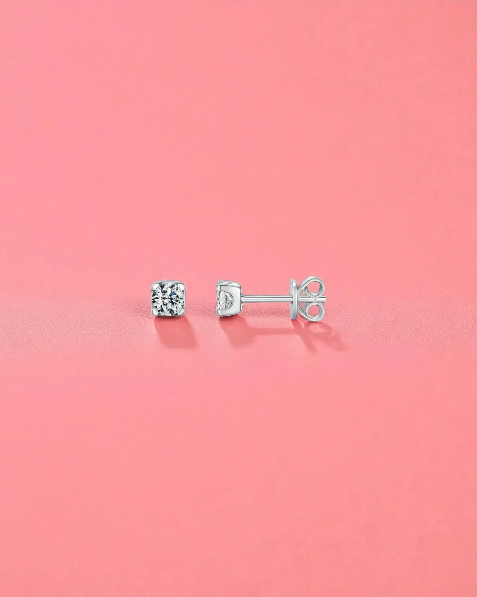 4mm Round brilliant cut moissanite studs displayed on a pink background, showcasing their brilliant sparkle and sterling silver setting.