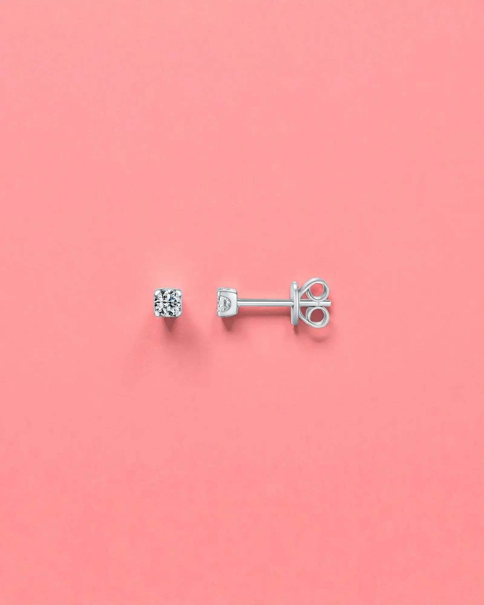 3mm Round brilliant cut moissanite studs on a pink background, showcasing their sterling silver and rhodium finish.