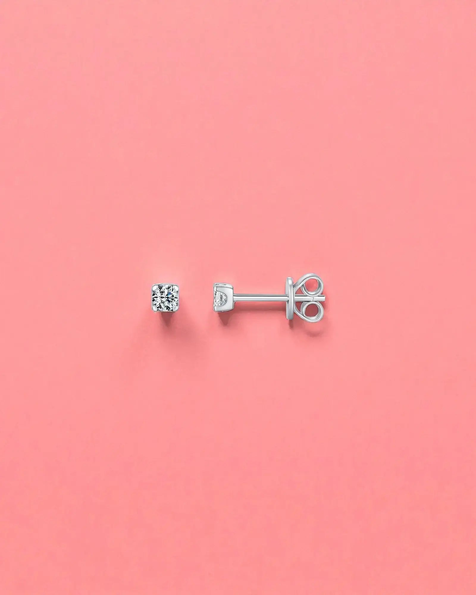 3mm Round brilliant cut moissanite studs on a pink background, showcasing their sterling silver and rhodium finish.