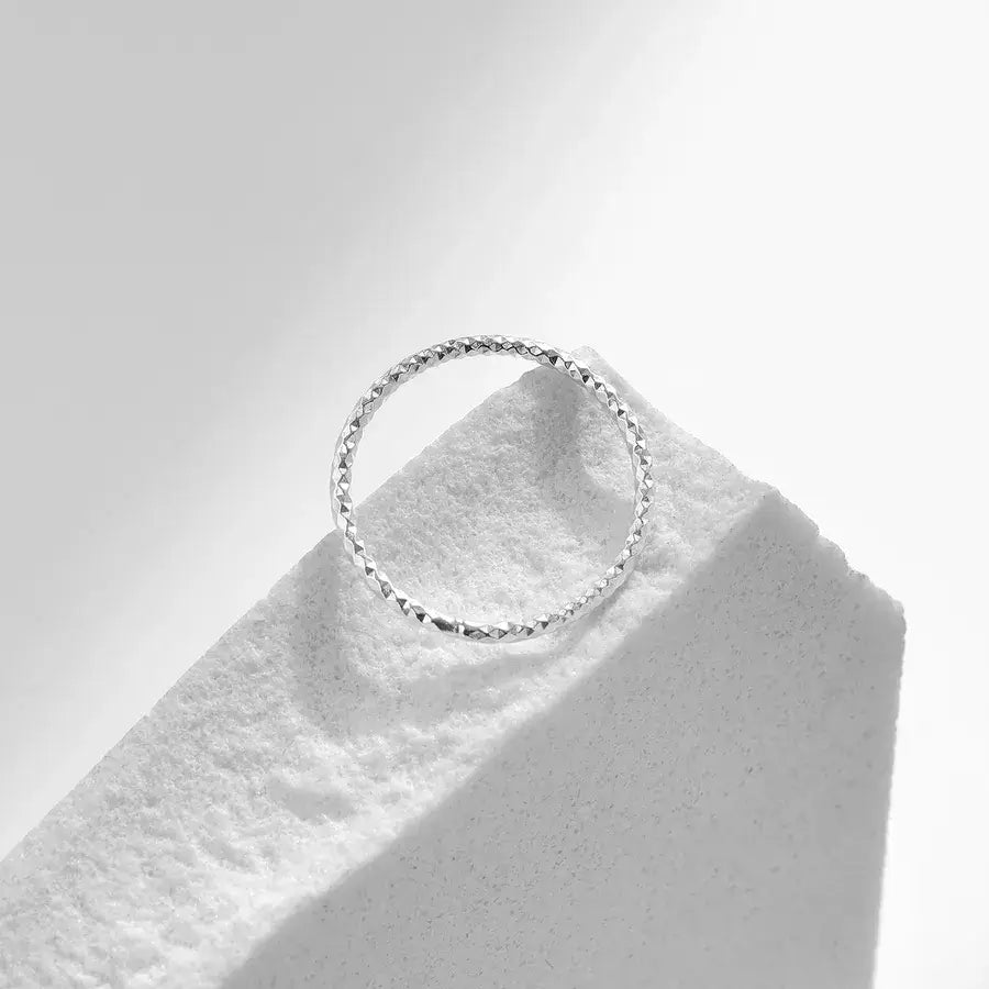 Silver wave textured ring on a light background, showcasing its metallic shine and simple design for everyday wear.
