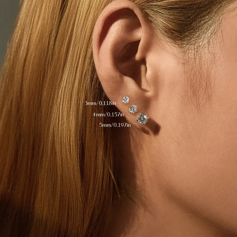 Close-up of a model's ear with three sizes of earrings: 3mm, 4mm Round brilliant cut moissanite studs, and 5mm.
