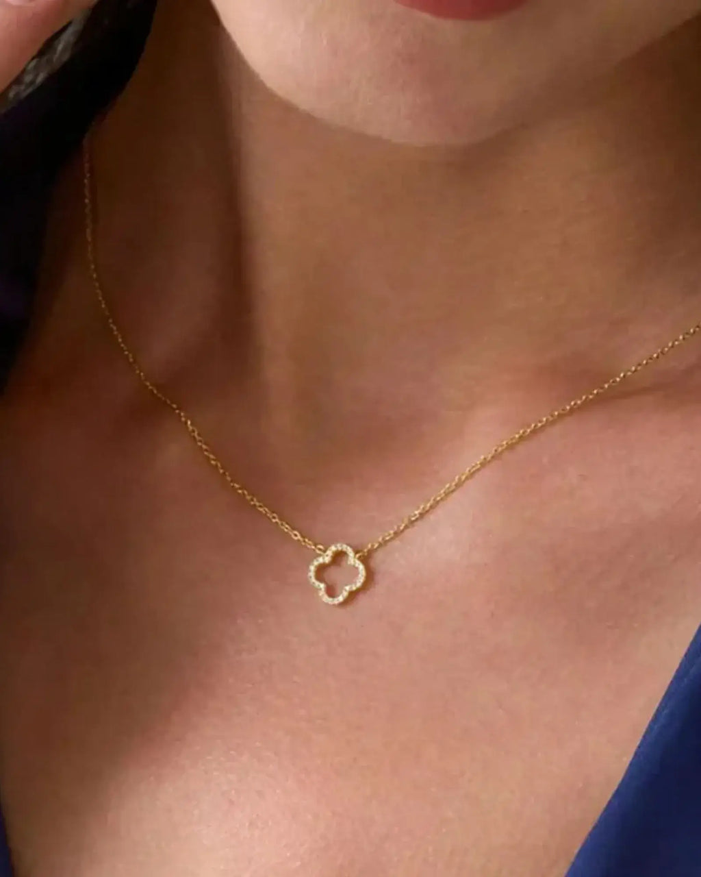 925 sterling silver clover pendant necklace worn on a model, showcasing its elegant flower design and 14K gold plating.