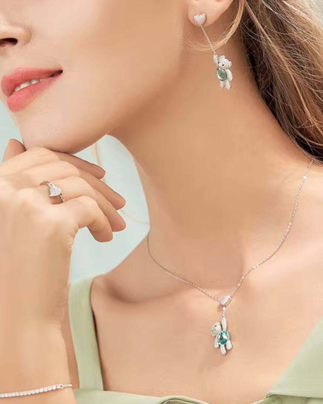 Model showcasing pink pavé heart and bear pendant necklace with matching earrings and ring, emphasizing playful elegance.