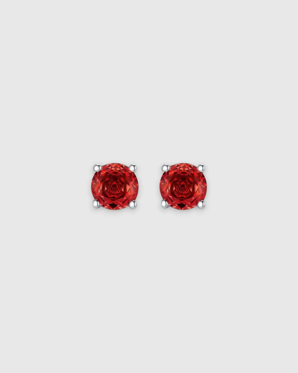 Pair of red gemstone stud earrings on a light gray background