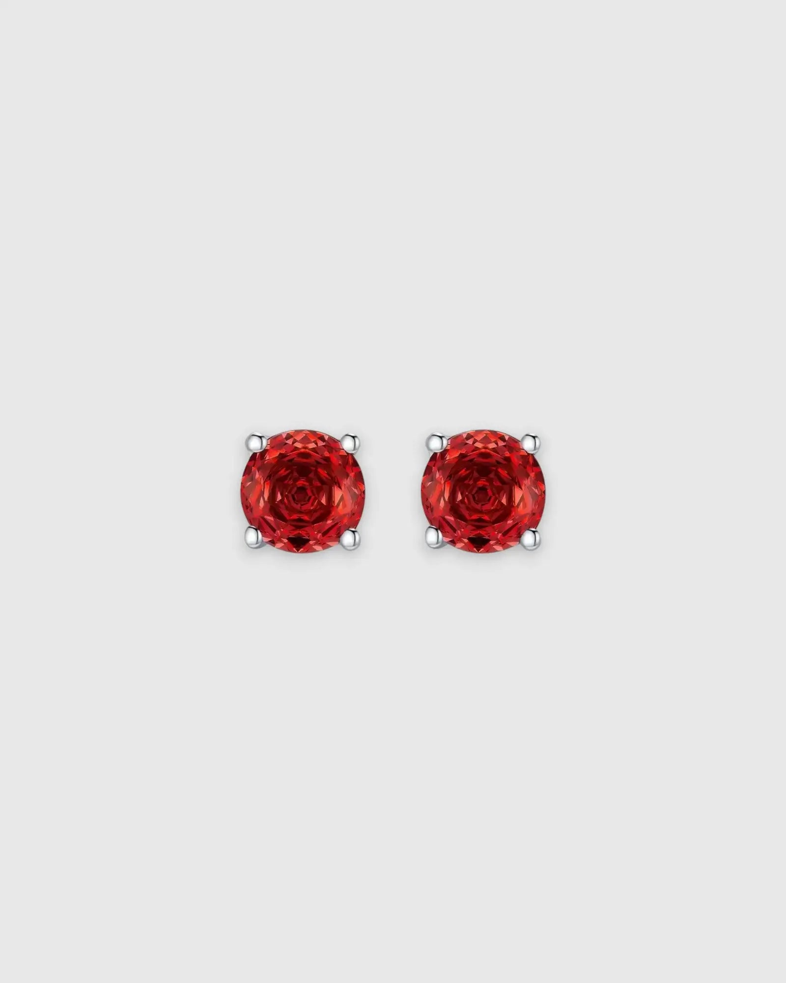 Pair of red gemstone stud earrings on a light gray background