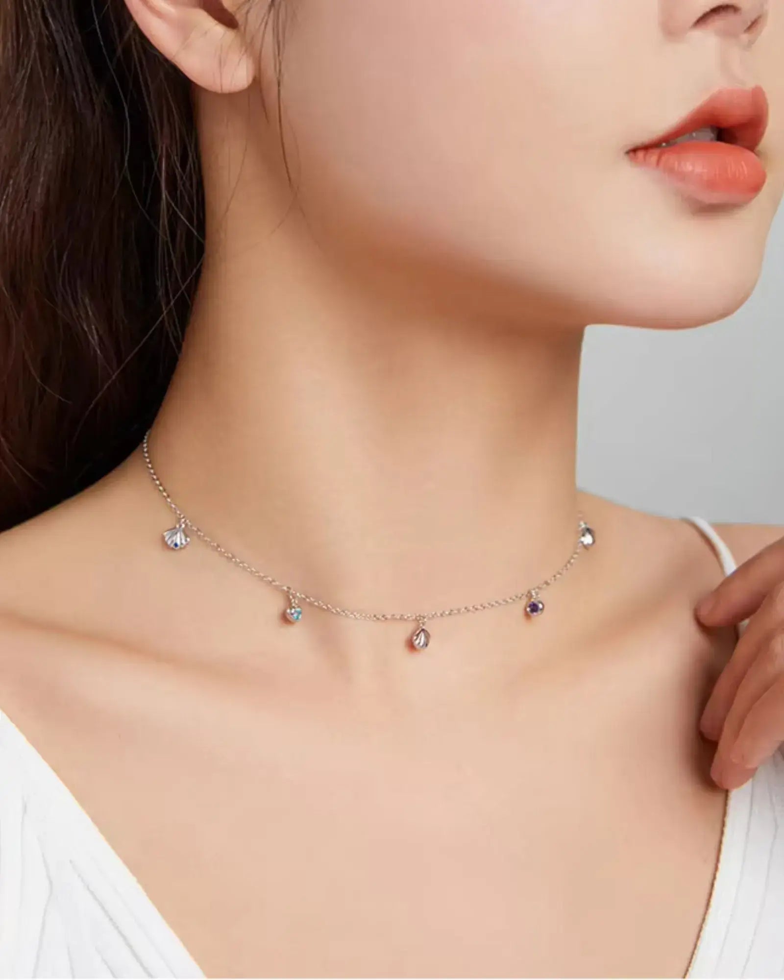 Scallop charm necklace in silver with blue zircon, showcasing ocean-inspired elegance in a layered style.