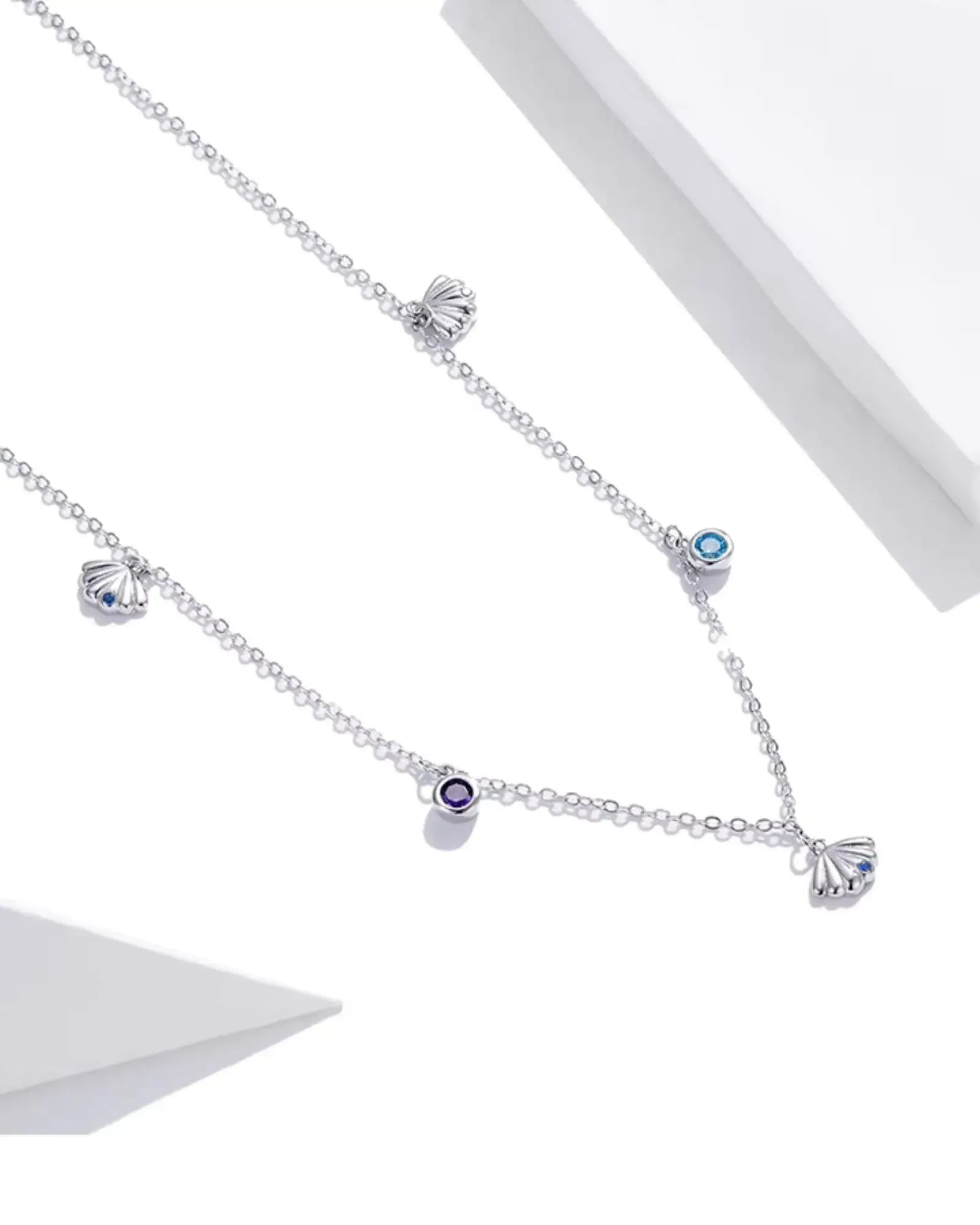 Scallop charm necklace in silver with blue and purple zircon, showcasing ocean-inspired elegance and adjustable design.