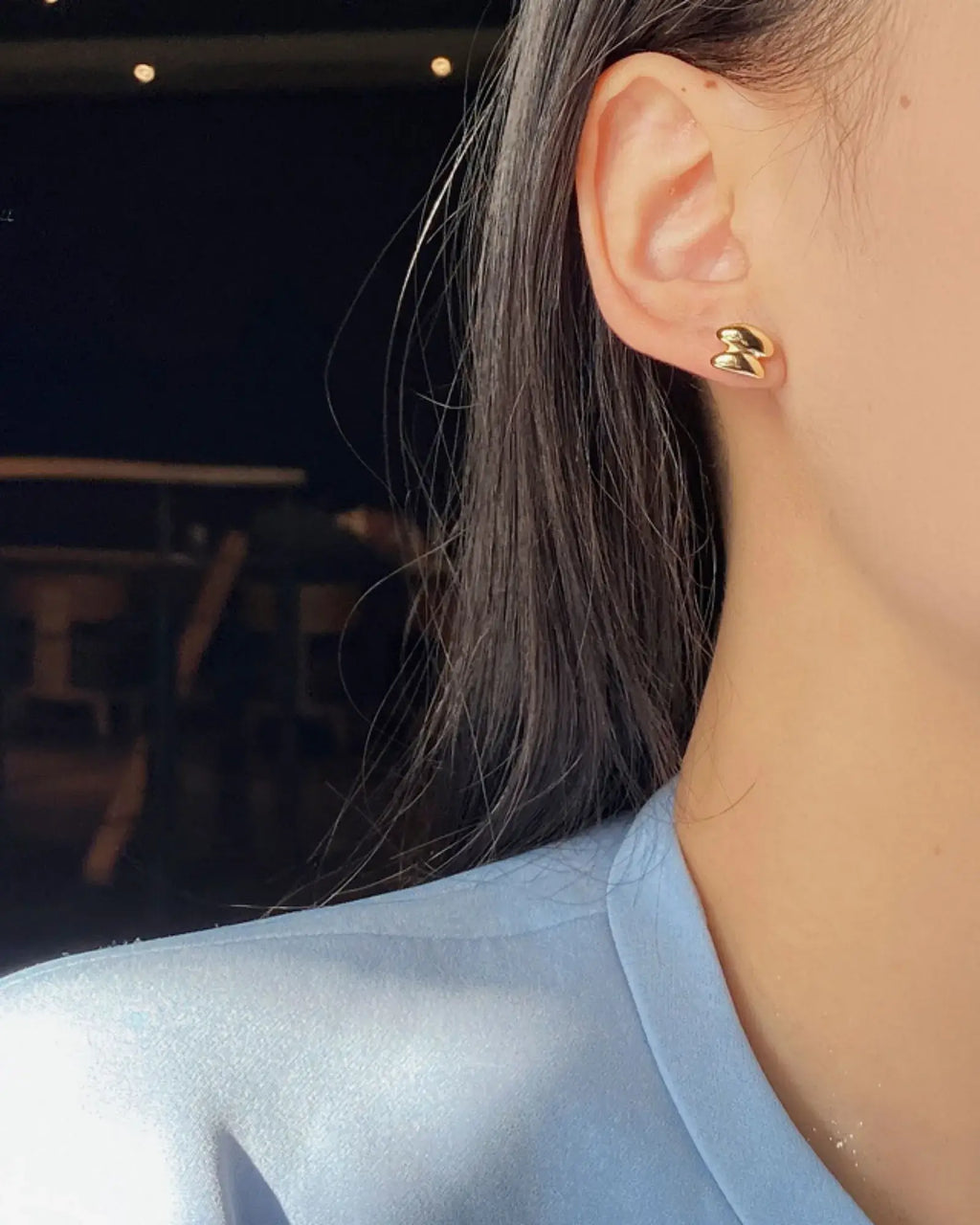 Close-up of Sculptura Ear Studs in 18k gold worn by a woman, showcasing a bold geometric design.