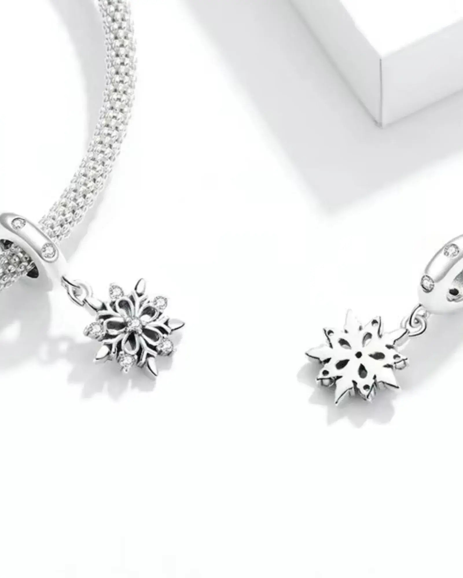 Elegant 925 sterling silver snowflake charms on a bracelet, featuring intricate pave settings and romantic design.