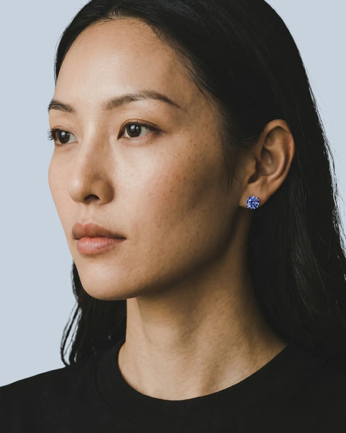 Woman wearing a blue earring against a light gray background