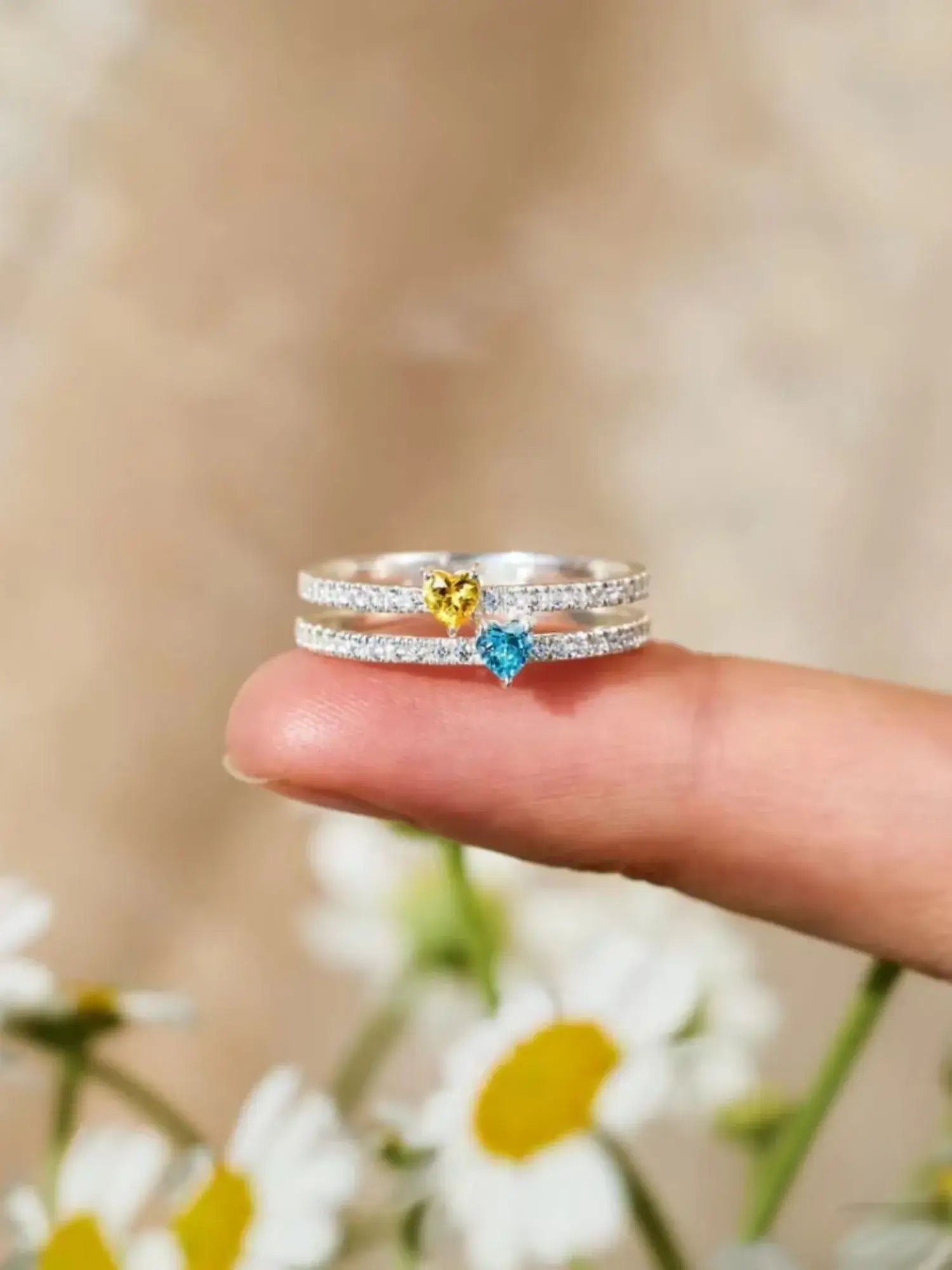 Two Heart Colourful Zircon Ring shown on a finger, featuring yellow and blue zircon stones set in sterling silver.