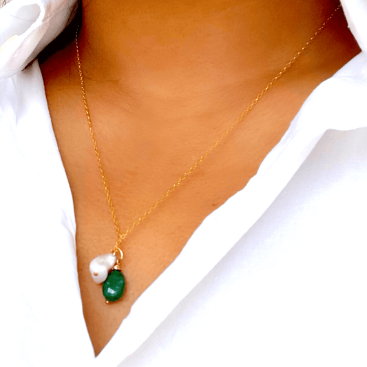 a woman wearing a white shirt and a emerald and pearl necklace