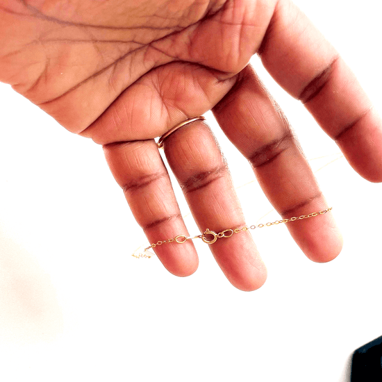 a person's hand holding a gold filled necklace