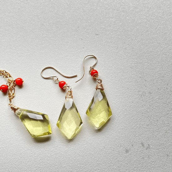 a pair of earrings with yellow glass and red beads