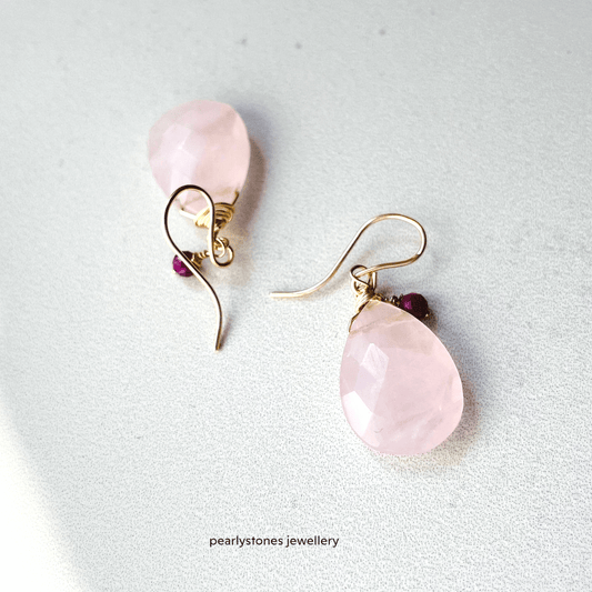 a pair of earrings with pink stones on them