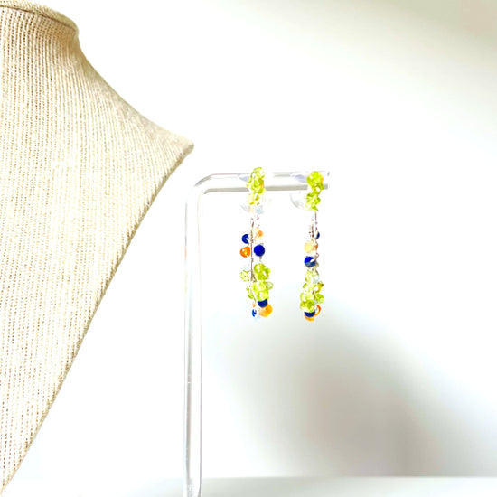 a pair of green and blue earrings sitting on top of a table