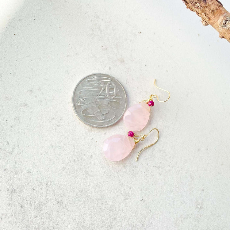 A pair of rose quartz and ruby earrings shown with a 20 cents coin to compare the size