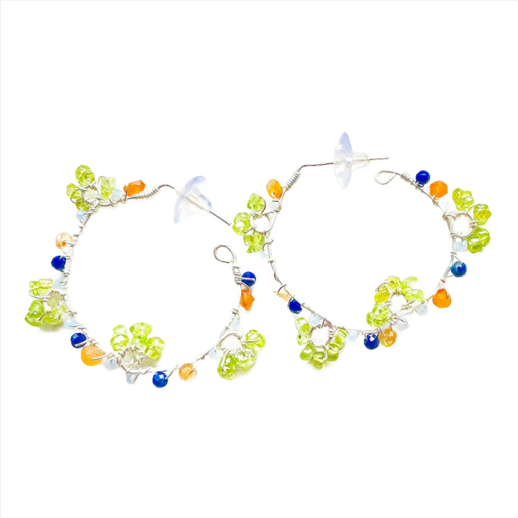 a pair of colorful beaded hoop earrings on a white surface